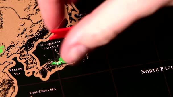 Человек стереть Японию с одним долларом монет на азиатской черной карте путешествия скретч — стоковое видео
