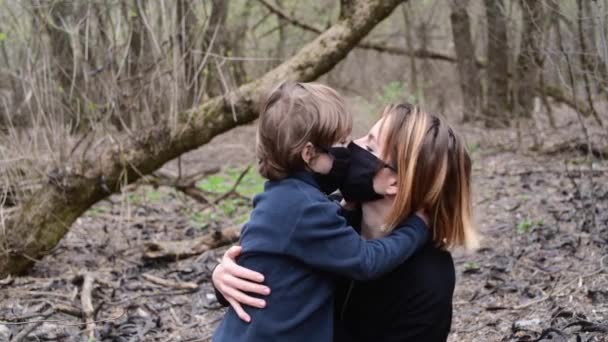 Mujer joven e hijo de pie en el bosque con máscara médica negra del virus Covid-19 — Vídeos de Stock