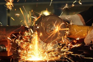 İşçi, öğütücü metali kesiyor ve bundan büyük miktarda kıvılcım çıkıyor.