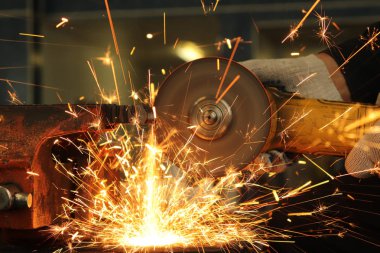 İşçi, öğütücü metali kesiyor ve bundan büyük miktarda kıvılcım çıkıyor.