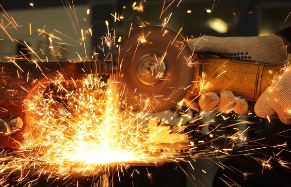 worker, grinder cuts metal and from this a huge amount of sparks