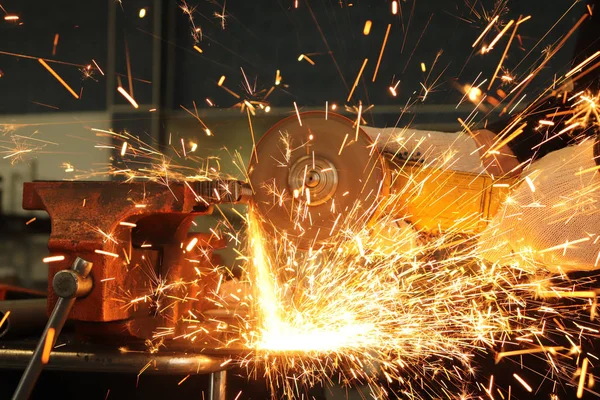 worker, grinder cuts metal and from this a huge amount of sparks