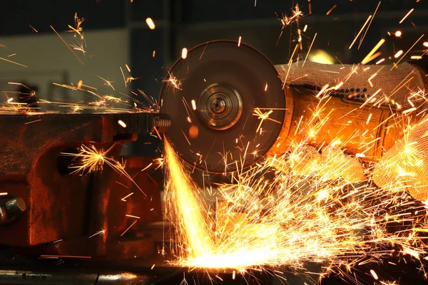 worker, grinder cuts metal and from this a huge amount of sparks