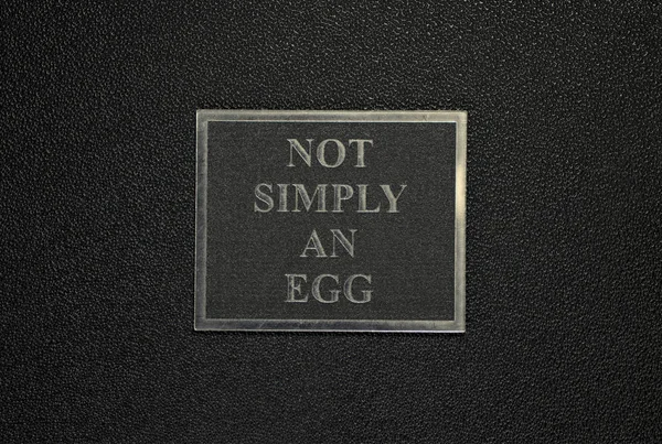 plate on a black matte background on which is written not simply an egg