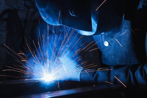 factory welder welds parts with a semi-automatic welding machine