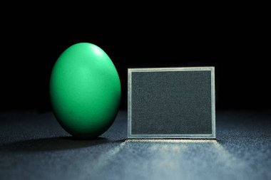 Siyah arka planda turkuaz yumurta. Metin için alanı olan siyah tabak.