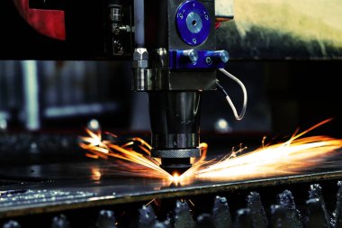 Metal bir levhayı kesen endüstriyel bir lazerin parlak ışığı. Sanayi lazeri üretimde.