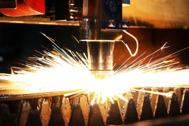 Metal bir levhayı kesen endüstriyel bir lazerin parlak ışığı. Sanayi lazeri üretimde.