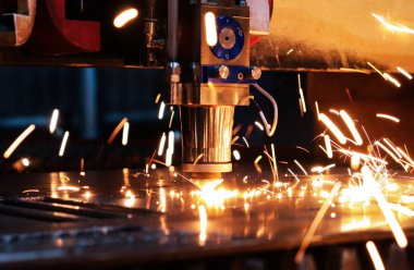 Lazer makinesi metal bir levhayı kesiyor ve parlak kıvılcımlar işlerinden uçup gidiyor. Metal fabrikasında lazer makinesi..
