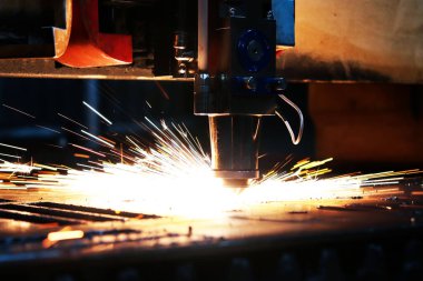 Metal bir levhayı kesen endüstriyel bir lazerin parlak ışığı. Sanayi lazeri üretimde.