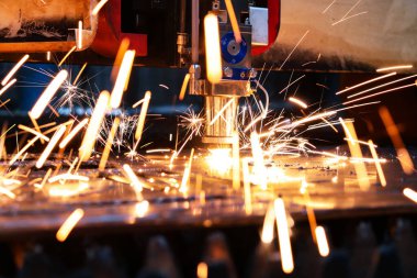  Endüstriyel lazer kalın bir metal tabakayı keser. Erimiş metal her yöne dağılır.