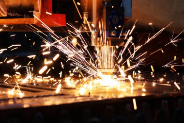  Endüstriyel lazer kalın bir metal tabakayı keser. Erimiş metal her yöne dağılır.