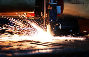 Metal bir levhayı kesen endüstriyel bir lazerin parlak ışığı. Sanayi lazeri üretimde.