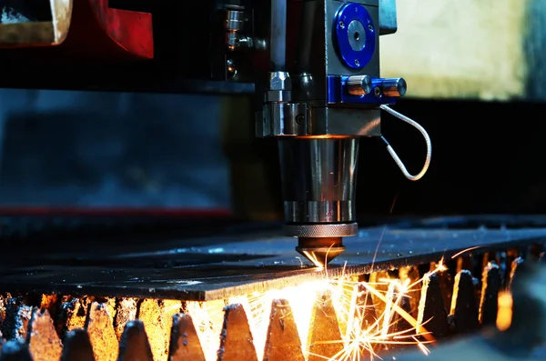 The laser machine cuts a metal sheet and bright sparks fly out of its work. Laser machine at a metalworking factory.