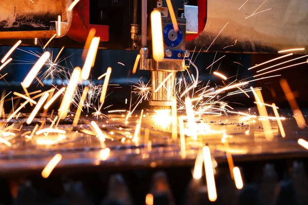 Industrial laser cuts a thick sheet of metal. Molten metal scatters in all directions