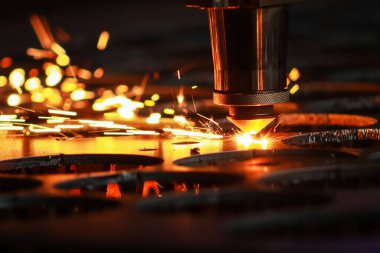 Lazer makinesi metal bir levhayı kesiyor ve parlak kıvılcımlar işlerinden uçup gidiyor. Metal fabrikasında lazer makinesi..