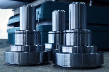 Masanın üzerinde duran makinenin üzerinde üç parça var. CNC makinelerinde metal parçaları