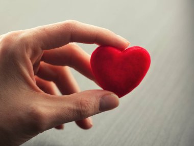 Küçük parlak kırmızı kalp tutan el