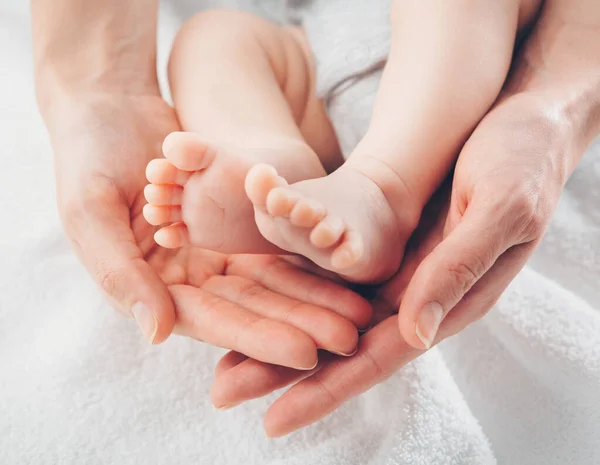 Pies de bebé en manos de madre. Mamá y su hijo. Concepto de familia feliz — Foto de Stock