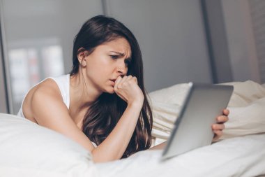 Tableti elinde tutan endişeli kadın.