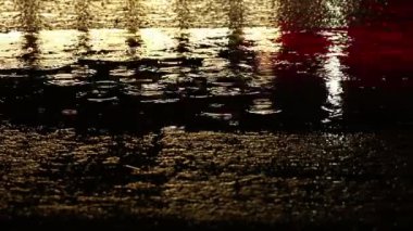 Gece su yüzeyindeki yağmur damlaları