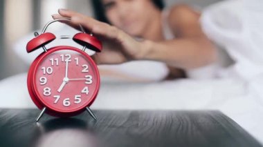 Güzel kız yatakta uyur, çalar saati kapatır ve uyumaya devam eder. Alarm saatine odaklan