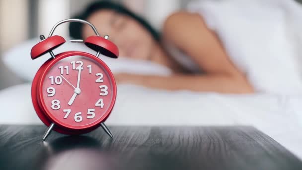 Beautiful girl sleeps in bed, turns off alarm clock and keeps sleeping. Focus on alarm clock — Stock Video
