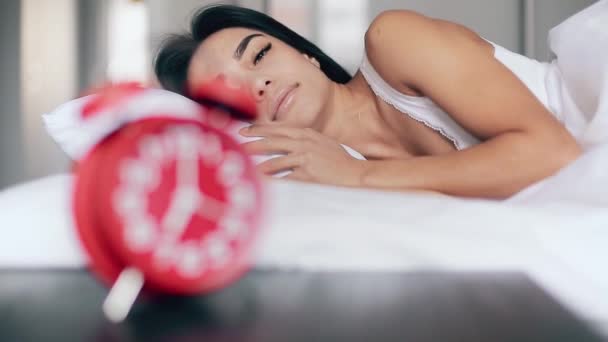 Menina bonita dorme na cama, desliga o despertador e continua dormindo — Vídeo de Stock