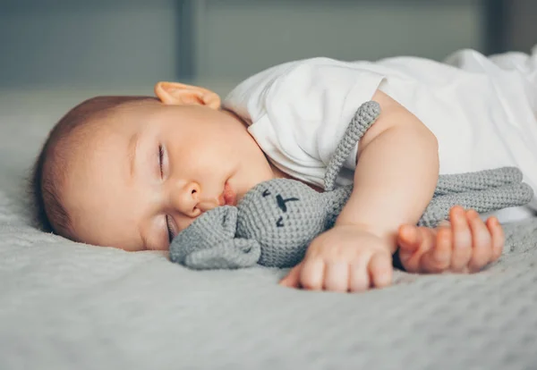 Dulce bebé recién nacido duerme con una liebre de juguete gris — Foto de Stock