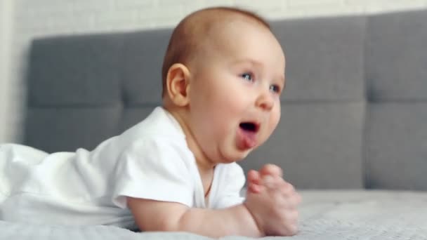 Een schattige pasgeboren baby jongen liggend op bed en hoest — Stockvideo