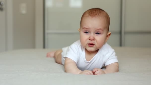 Bebé acostado en la cama mirando a la cámara y llorando — Vídeos de Stock