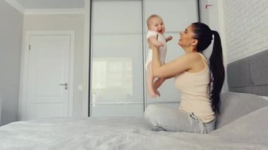 Mutlu kaygısız anne ve tatlı küçük çocuk ayaklarının üzerinde gülüyor. Yatakta uzanıyor, gülüyor, anne gibi gülüyor. Birbirimize sarılmaktan ve evde komik çocukla vakit geçirmekten keyif alıyoruz.