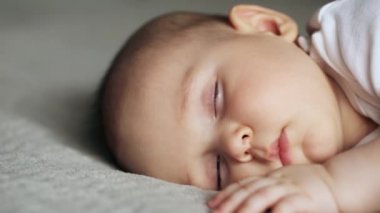 Gri battaniyenin üzerinde uyuyan tatlı çocuk.