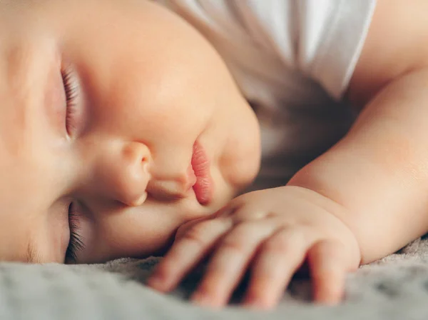 Retrato de cerca de un hermoso bebé dormido en gris — Foto de Stock