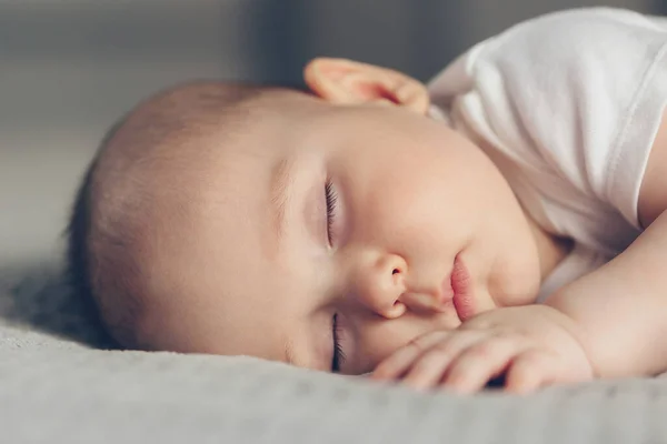 Retrato de cerca de un hermoso bebé dormido en gris — Foto de Stock