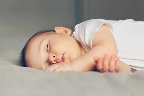 Retrato de cerca de un hermoso bebé dormido en gris — Foto de Stock