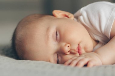 Gri üzerinde uyuyan güzel bir bebeğin yakın plan portresi