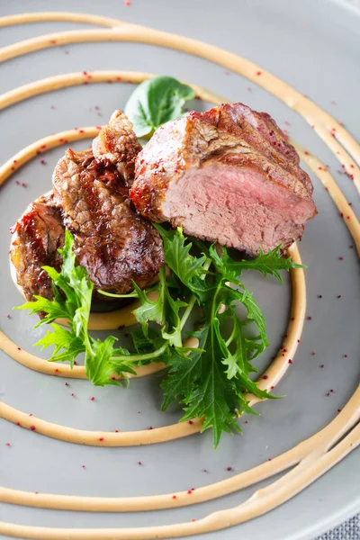 Heerlijke gegrilde rundvlees medaillons met saus en salade geserveerd op grijze plaat — Stockfoto