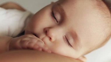 Huzurlu bir uykunun yakın plan portresi anne kucağında bebek..
