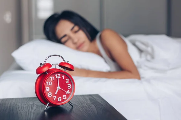 Wekker close-up en jonge slapende vrouw in de slaapkamer — Stockfoto