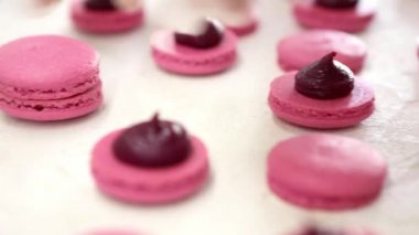 Pembe kurabiyeler yapıyorum. İki parça badem kurabiyesiyle dut kremasını birbirine bağlarken yakın çekim.