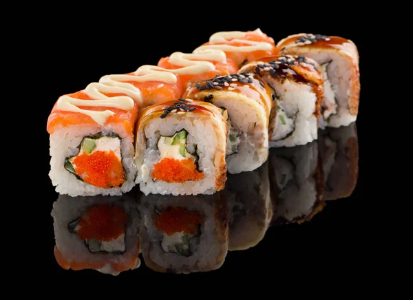 Zestaw dwóch różnych bułek sushi z łososiem, serem, ogórkiem, kawiorem tobiko, węgorzem, sosem i sezamem izolowanych na czarnym tle z odbiciem — Zdjęcie stockowe