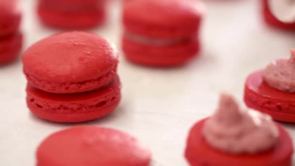 Rode Macarons aan het maken. Close-up shot van het verbinden van twee helften macarons met aardbeiencrème — Stockvideo