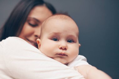 Huzurlu, güzel bir çocuğun ve gülümseyen bir annenin yakın plan portresi. Annenin elindeki bebek. Sağlık ve tıbbi aşk kadını anneler günü konsepti.