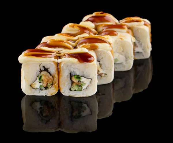 Sushi roll with eel, cheese, cucumber, chive and unagi sauce isolated on black background with reflection — Stock Photo, Image