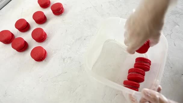 Chefs handen verpakken vers gebakken rode aardbei macaroon in container — Stockvideo