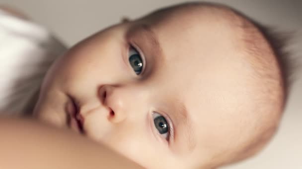 Κοντινό πλάνο πορτραίτο ενός ήσυχου κοιμισμένου αγοριού στην αγκαλιά της μητέρας. Το μωρό κοιτάζει την κάμερα.. — Αρχείο Βίντεο