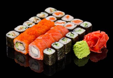 Zencefil ve wasabi karışımlı çeşitli suşi maki seti, siyah arkaplanda yansımayla izole edilmiş.