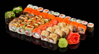 Zencefil ve wasabi karışımlı çeşitli suşi maki seti, siyah arkaplanda yansımayla izole edilmiş.