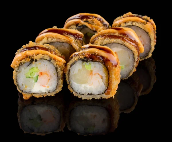 Жареный суши-ролл Урамаки с креветками, гребешками, сыром, огурцом, авокадо и соусом на черном фоне с отражением — стоковое фото